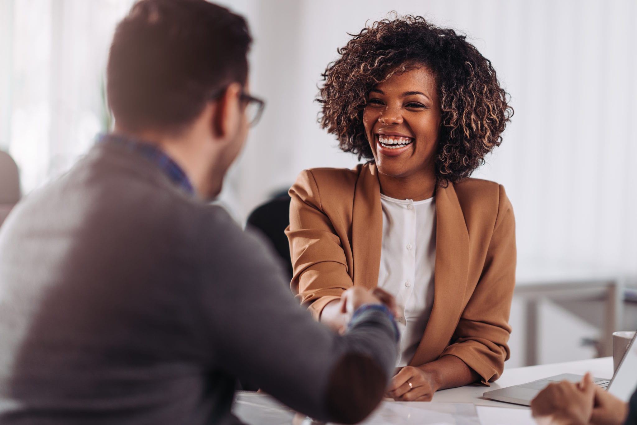 Happy businesswoman shaking hands with colleague after successful meeting.